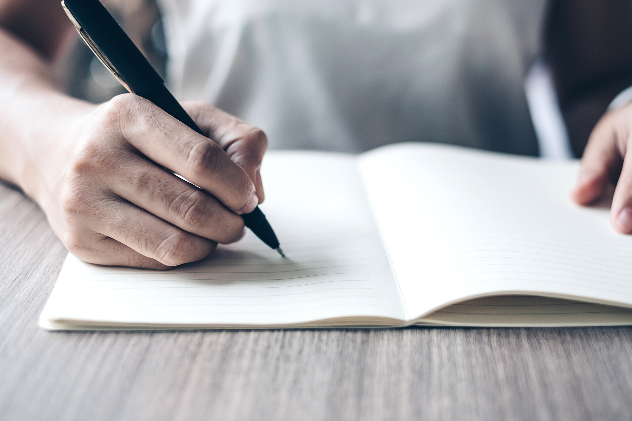 Woman at a table writing in a journal