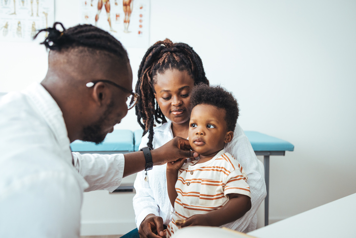 Photo shows a male pediatrician listening to a toddler's heartbeat/Getty Images