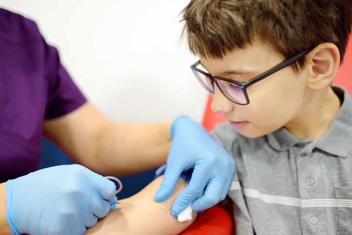 Photo shows a nurse drawing blood from a child using a butterfly needle/Getty Images