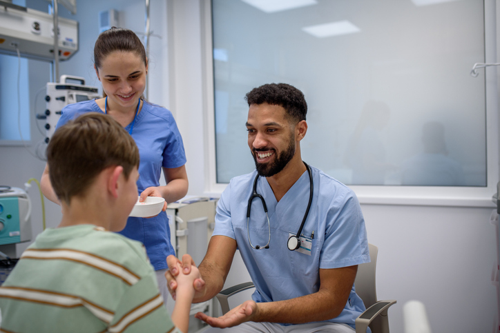 Photo shows a doctor and nurse speaking to a young male patient in the hospital/Getty Images