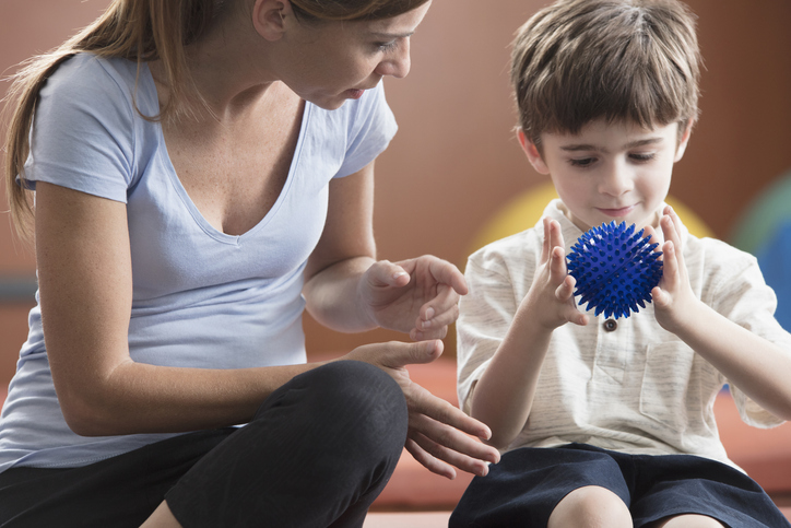 Photo shows a child working with a physical therapist/Getty Images