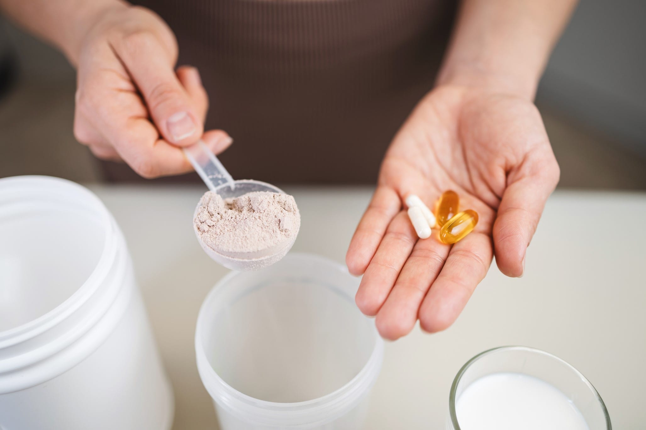 Hands holding supplement power and pills