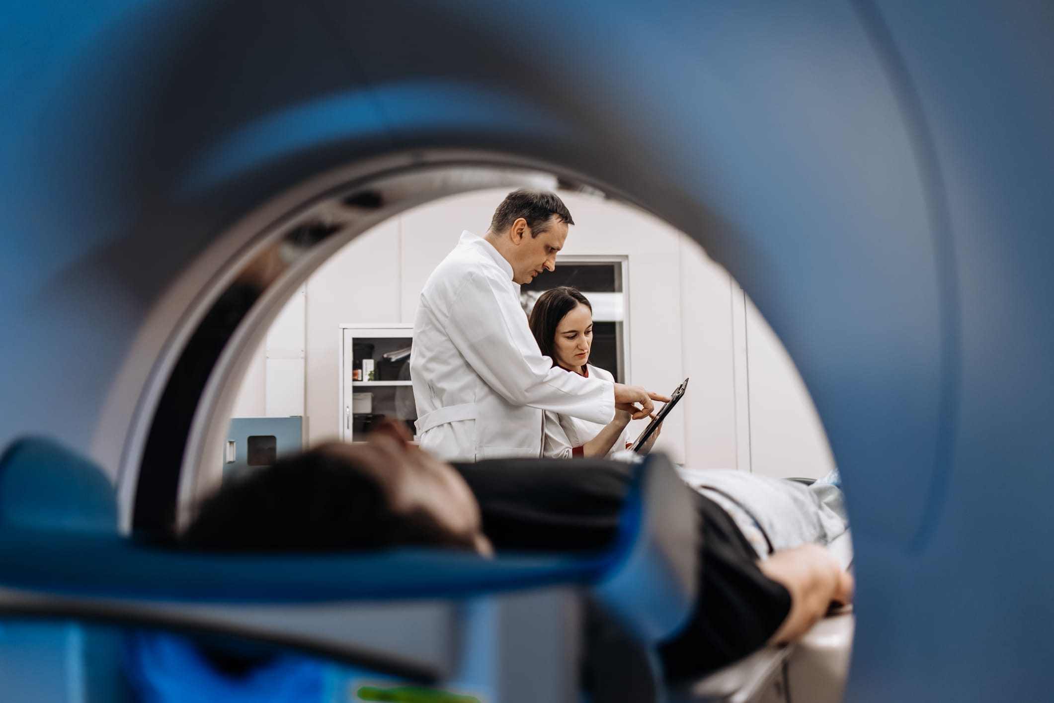 Doctors looking at data from an MRI while patient is in machine