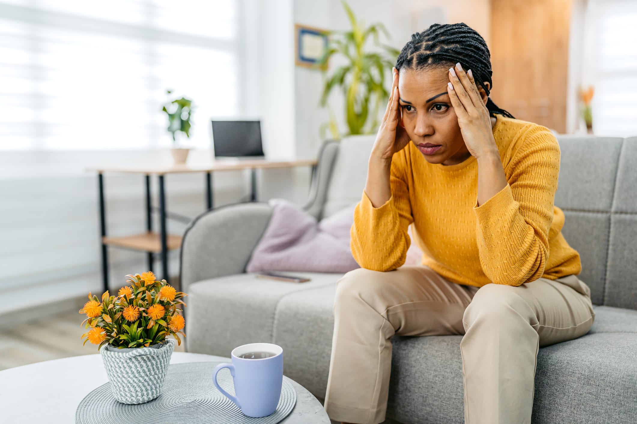 Woman sitting on the sofa holding her head