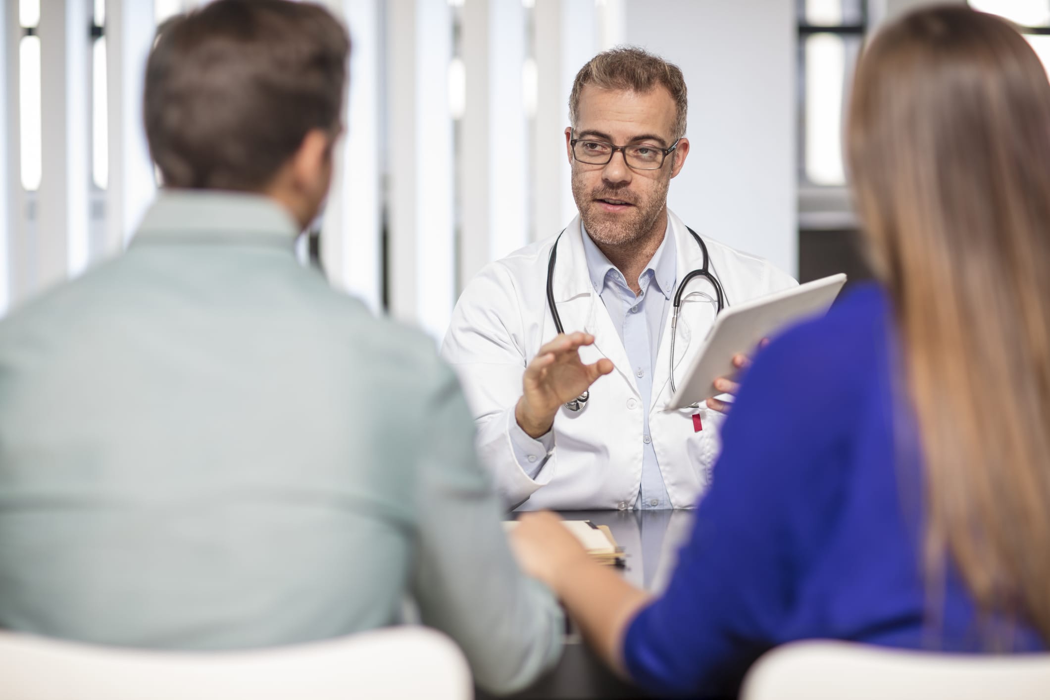 Couple holding hands as they speak with doctor